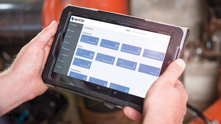 Person holding tablet with Synca dashboard showing